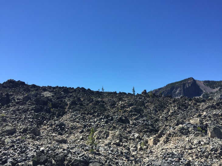 Rocky hillside with volcanic boulders on a blue sky day.