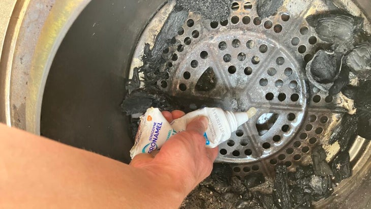 A hand squeezing Vaseline and sawdust out of a toothpaste tube to start a fire. 