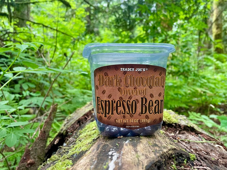 A plastic container of Trader Joe's dark chocolate-covered espresso beans on a log. 