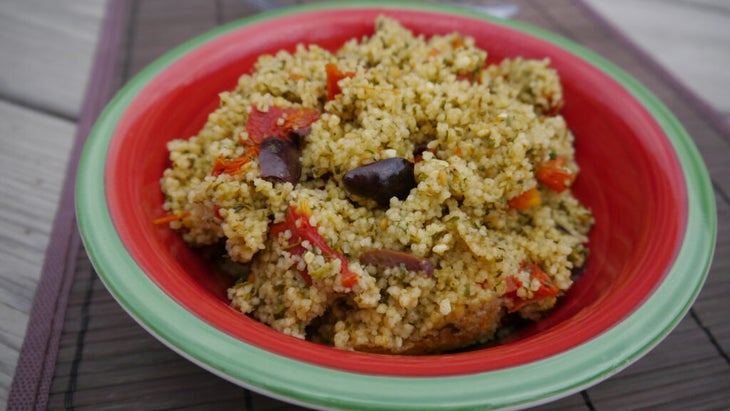 mediterranean couscous with olives and sundried tomatoes in a colorful bowl outdoors