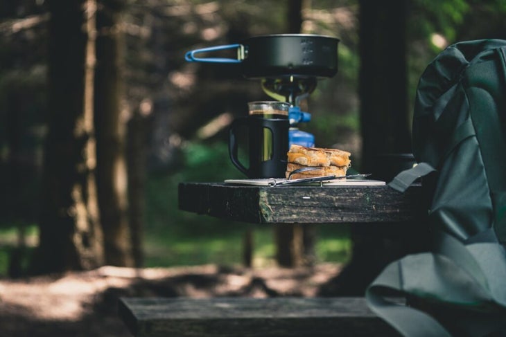 coffee in a french press on a picnic table in the forest