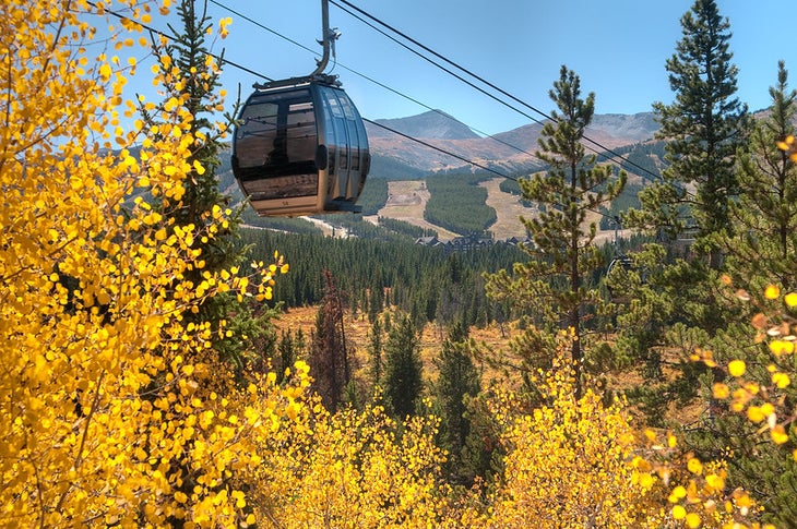 A Breckenridge, Colorado, gondola moves overhead among fall foliage
