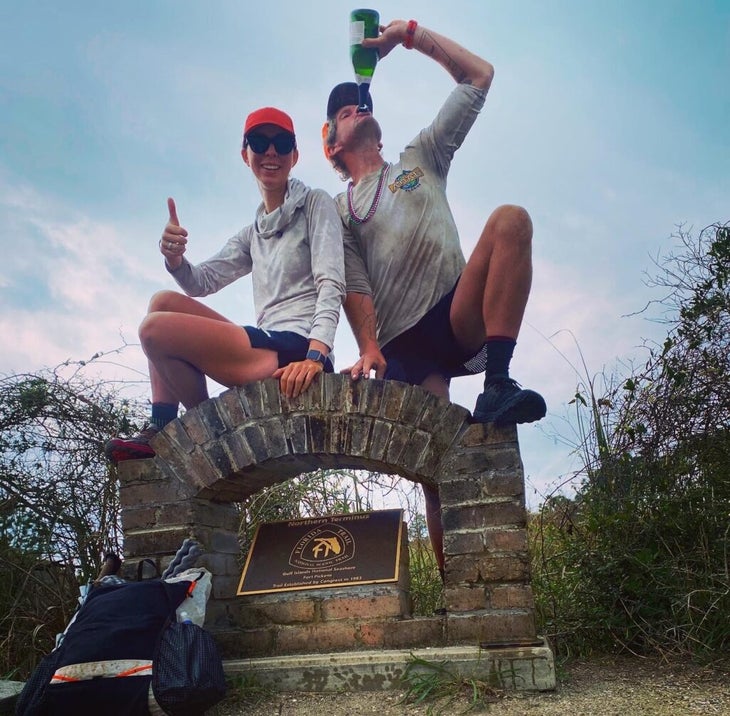 Two hikers pose next to a monument for the Florida Trail