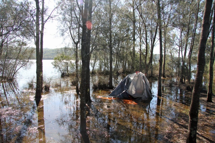 a tent footprint swamped with water in a very rainy campsite. 