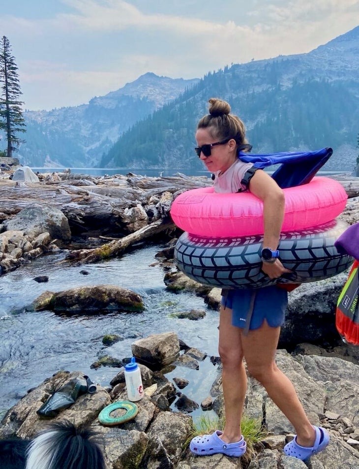 A hiker with two inner tubes around her waist in front of an alpine lake