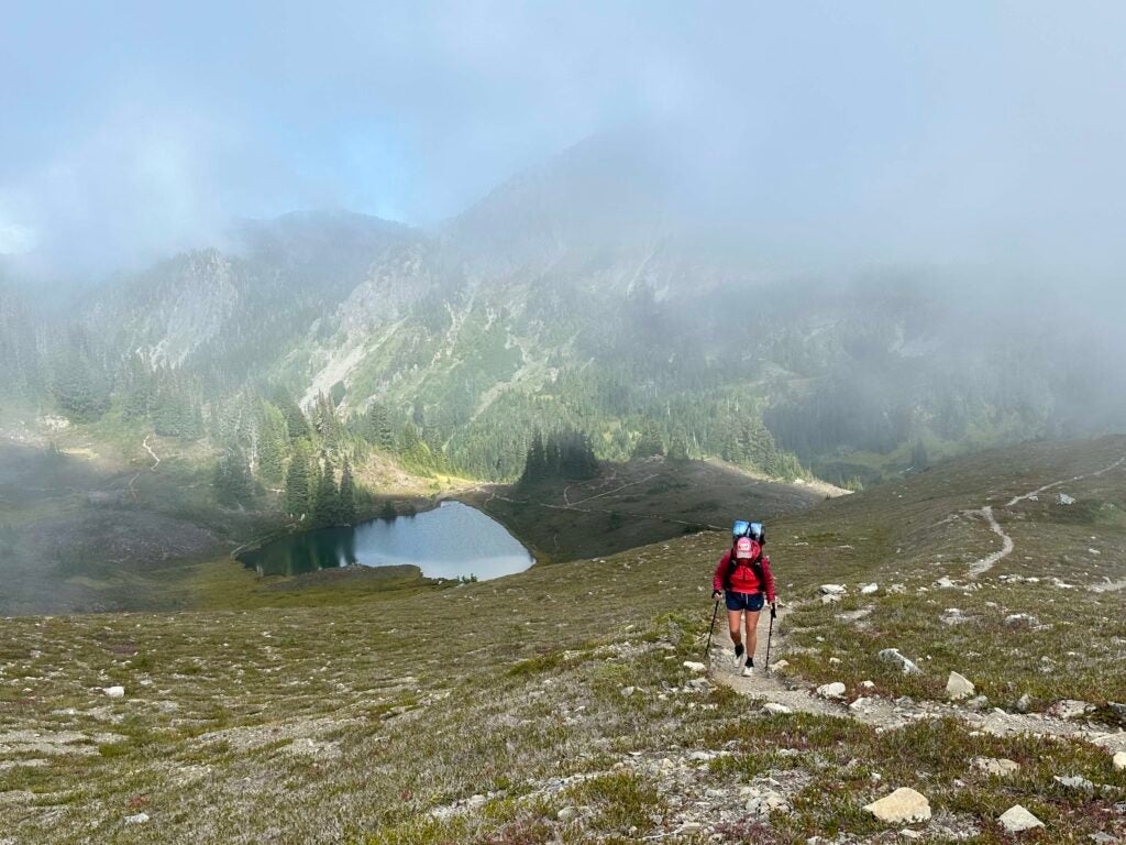 A female hiker hiking uphill above a lake