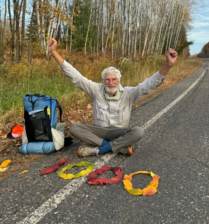 A hiker poses with leaves spelling out "1000"