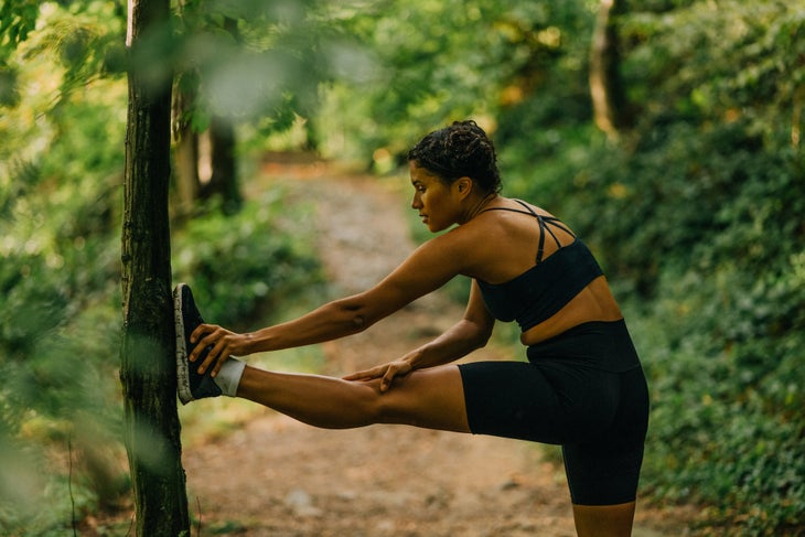 Woman stopping to stretch on trail