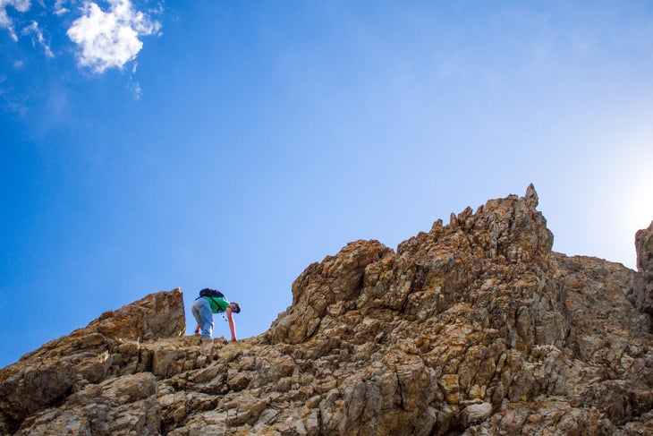 Teenage boy reaching mountain peak, Borah Peak, Idaho