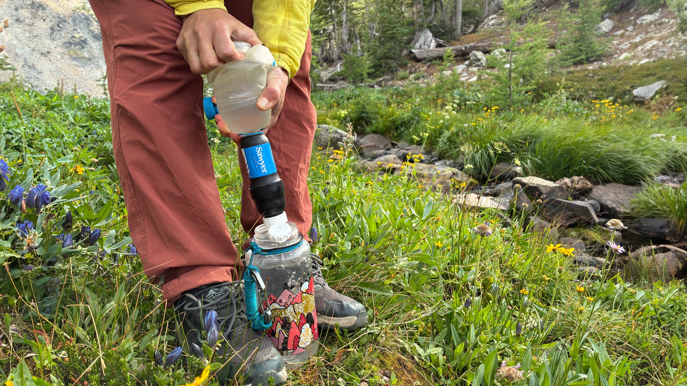Tester filters water into Nalgene bottle using Sawyer Squeeze Water Filtration System with Cnoc water bladder.