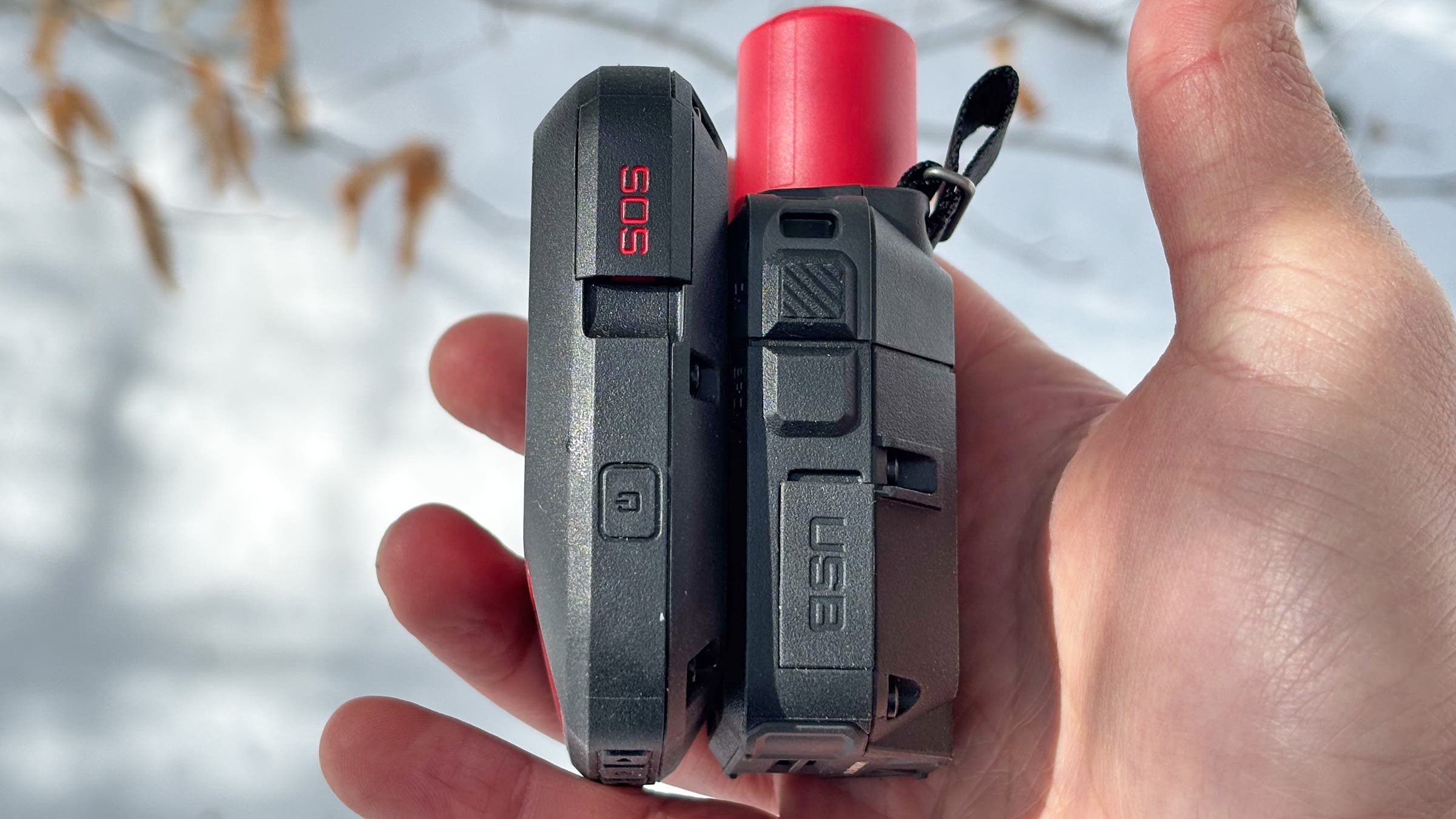 Garmin InReach Mini 3 Plus vs Messenger Plus satellite communicator side by side comparison, Backpacker's pick for best satellite communicator, held in a hand against a snowy outdoor background to show its compact and rugged design.