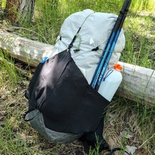The Charlie 32L Pack leaning against a log in the grass