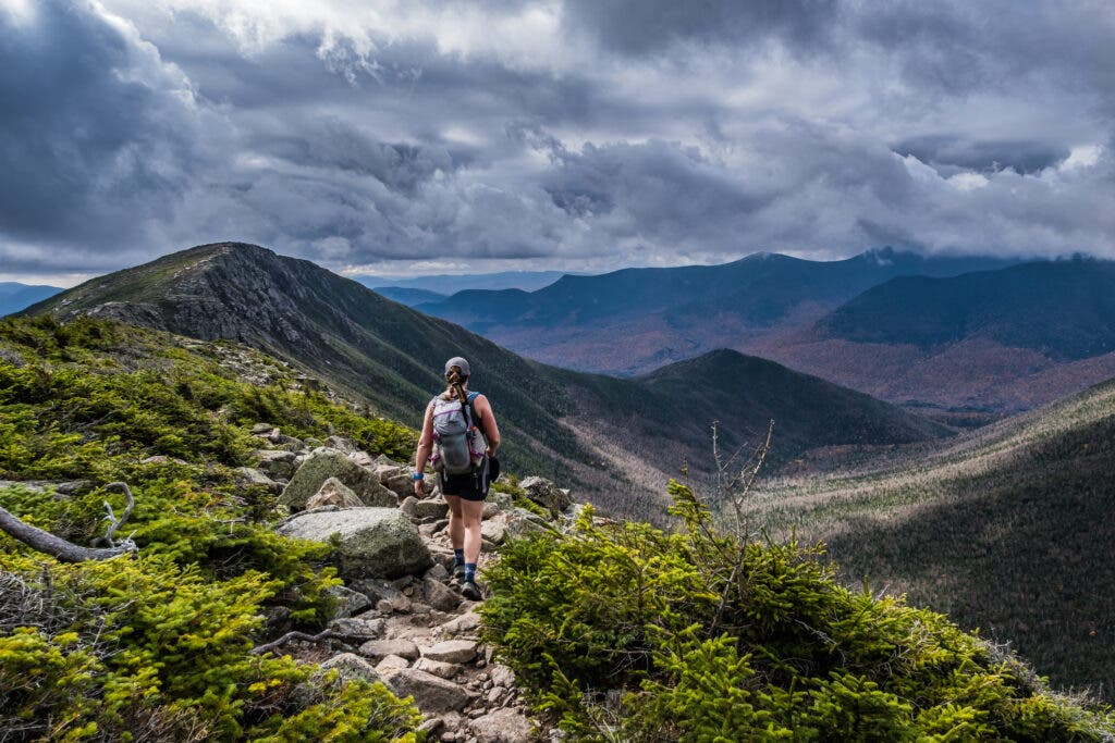 A hiker in the White Mountains of New Hampshire approaches the next peak visible in the distance.